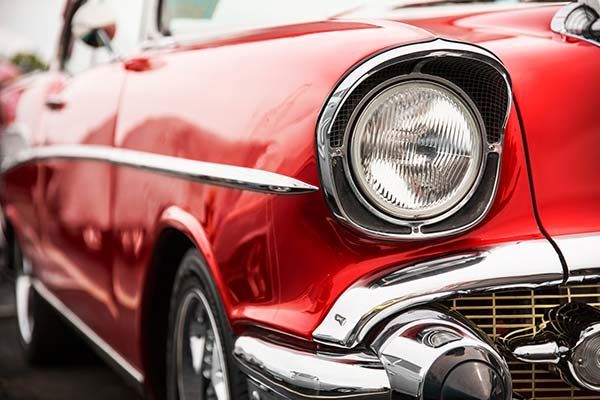 Red and chrome classic convertible car detail with a round headlight.