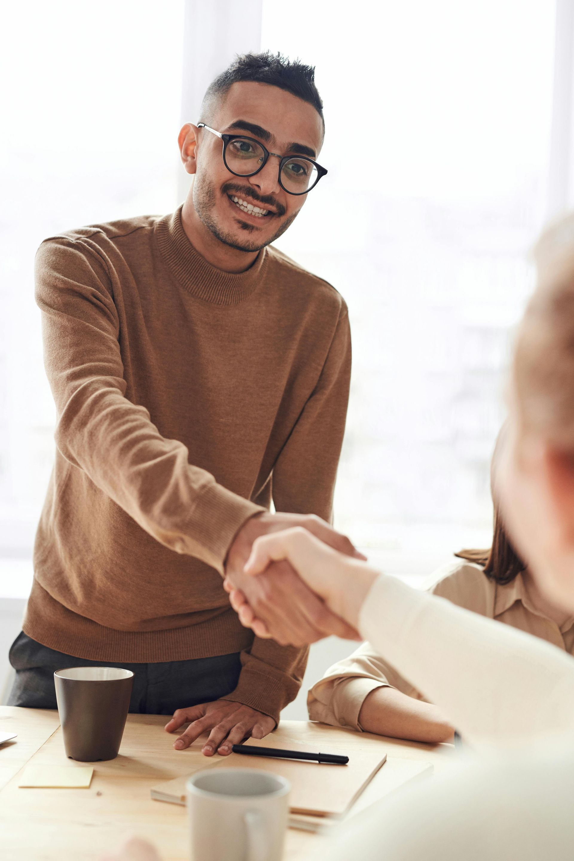 Man shaking hands at a table with someone off camera