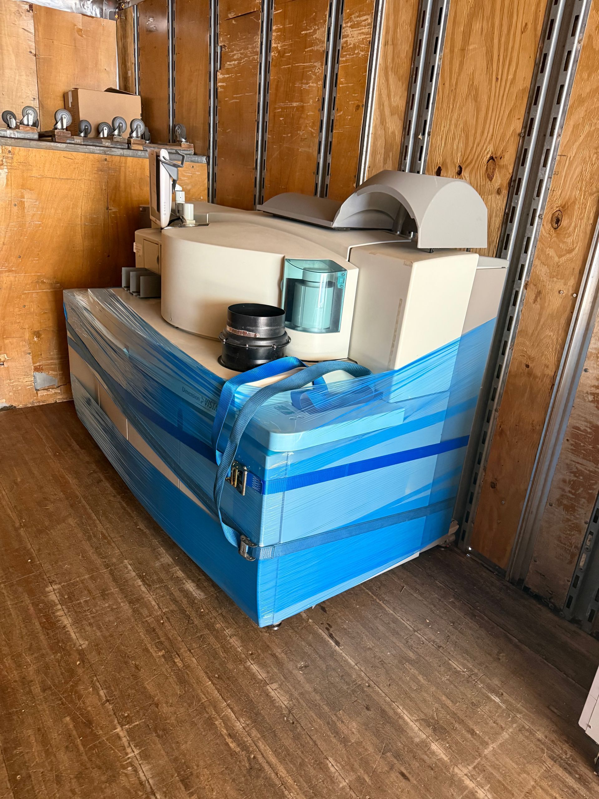 Blue tool case and white equipment on a wooden shelf in a small shed or workshop.