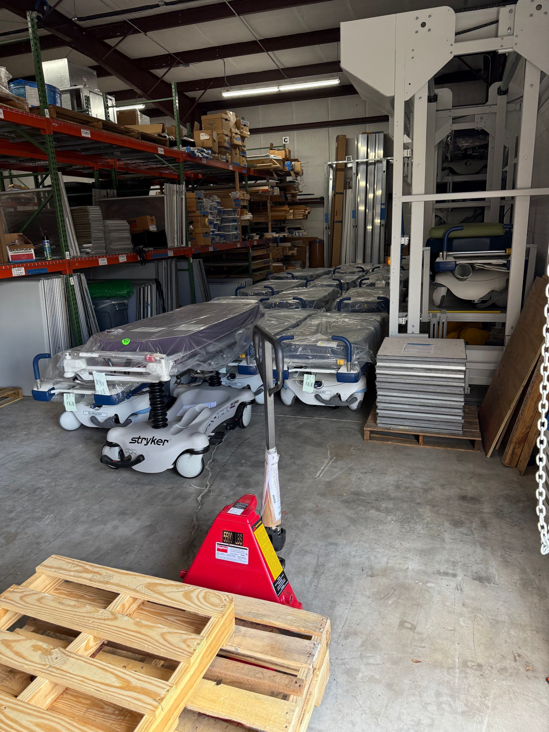 Warehouse aisle with stacked pallets, wrapped goods, and metal shelving under industrial lighting