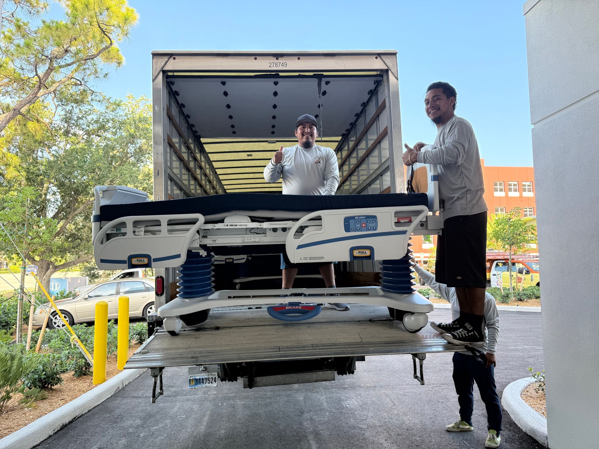 Men loading a white car onto a truck at a building entrance