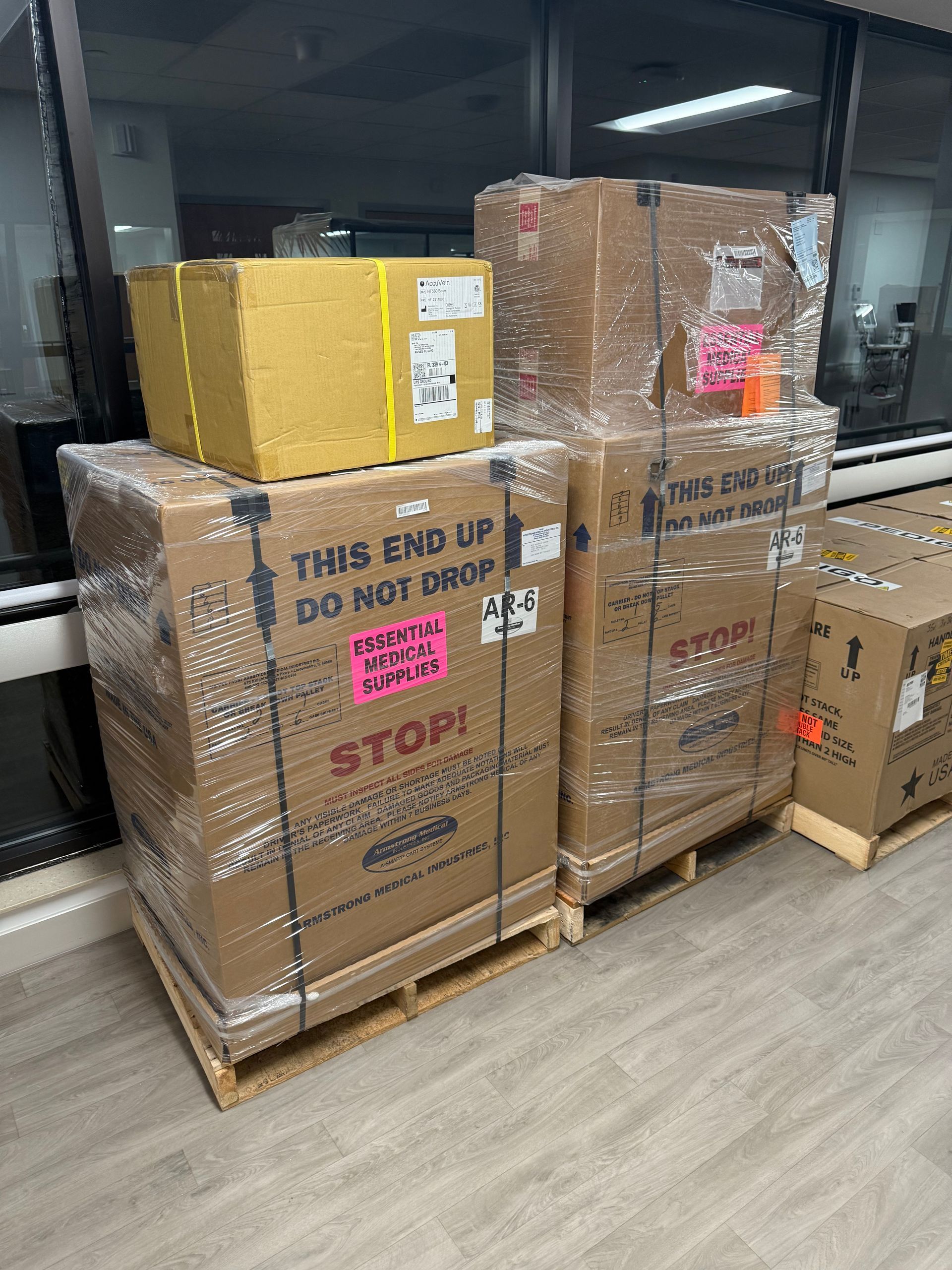 Stacked palletized cardboard boxes in a warehouse, including a yellow box and a carton marked “STOP!”