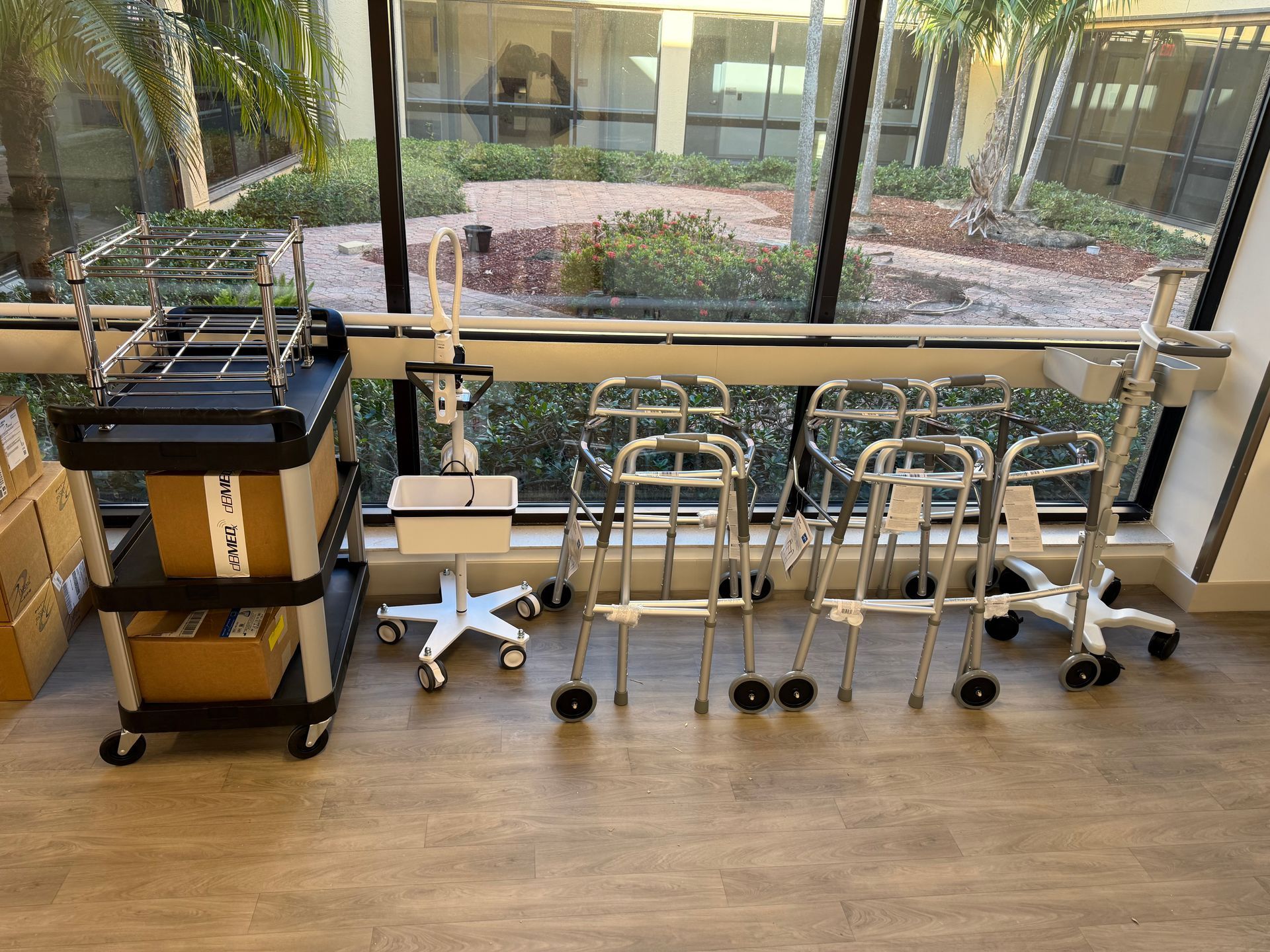 Hospital corridor with wheelchairs, walkers, and a cart lined up by a window
