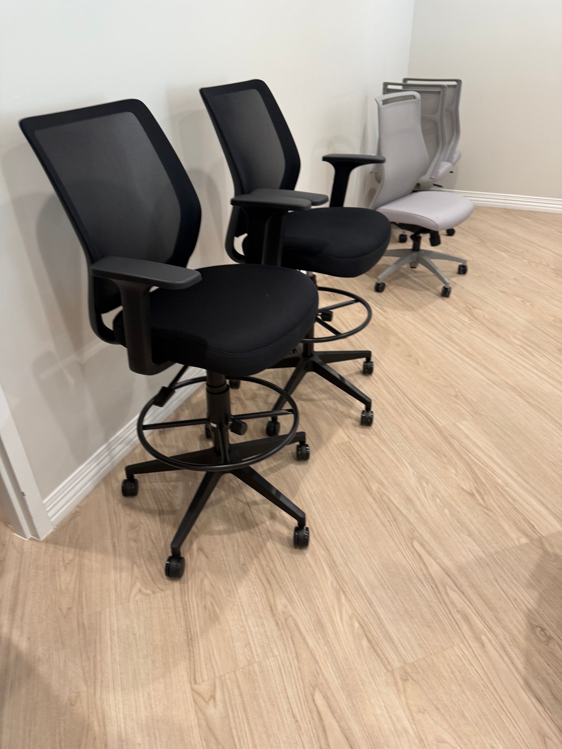 Three office chairs lined up against a wall on a light wood floor.