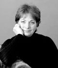 Black-and-white portrait of a smiling person resting their chin on their hand.