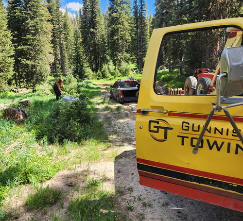 A yellow gunnis towing truck is parked on a dirt road