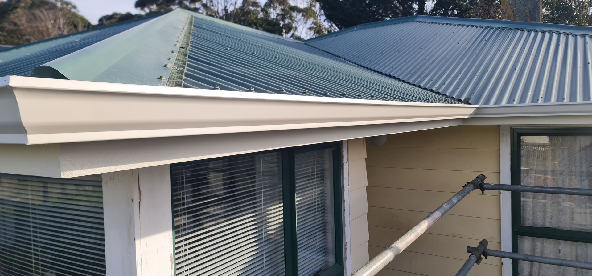 Dark gray tiled roof with dormers and a skylight on a brick house
