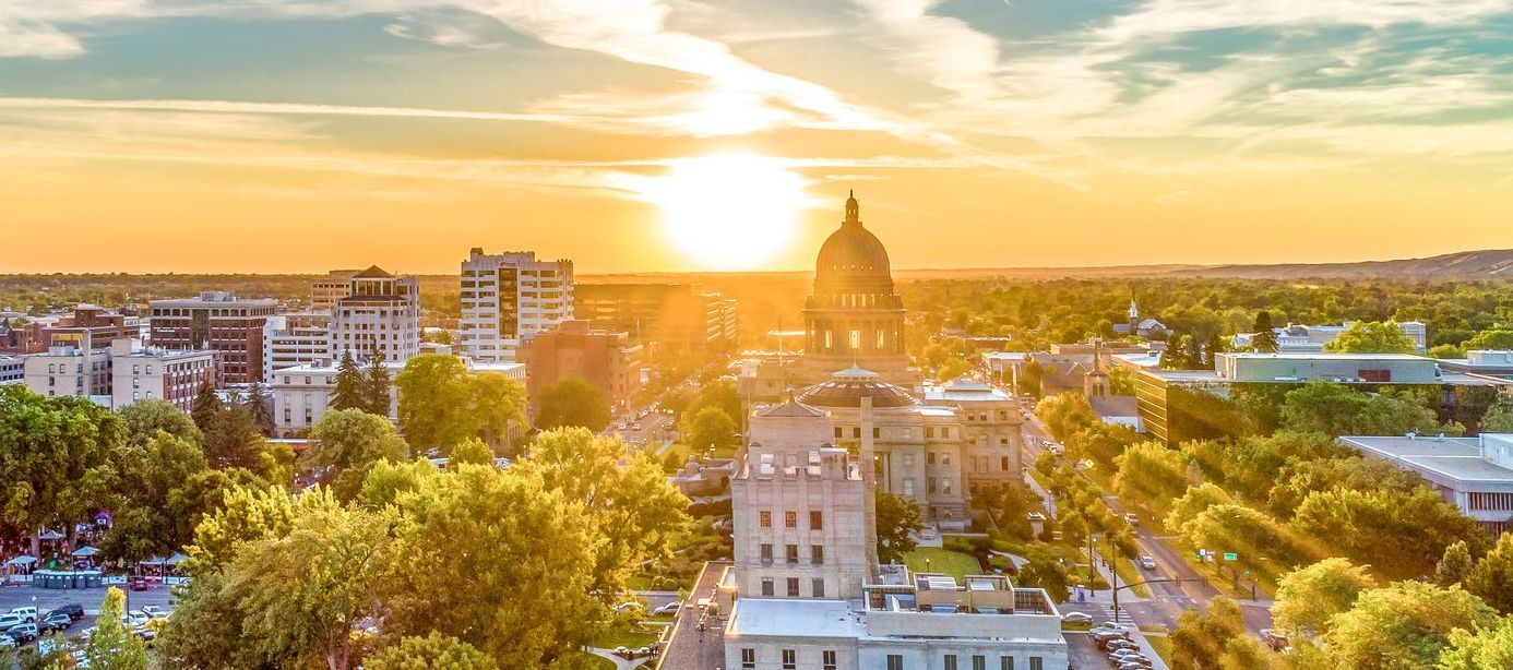An aerial view of Boise at sunset with a dome in the background.