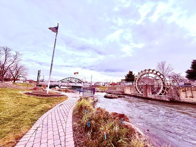 A brick walkway leading to a river with a bridge in the background in Caldwell