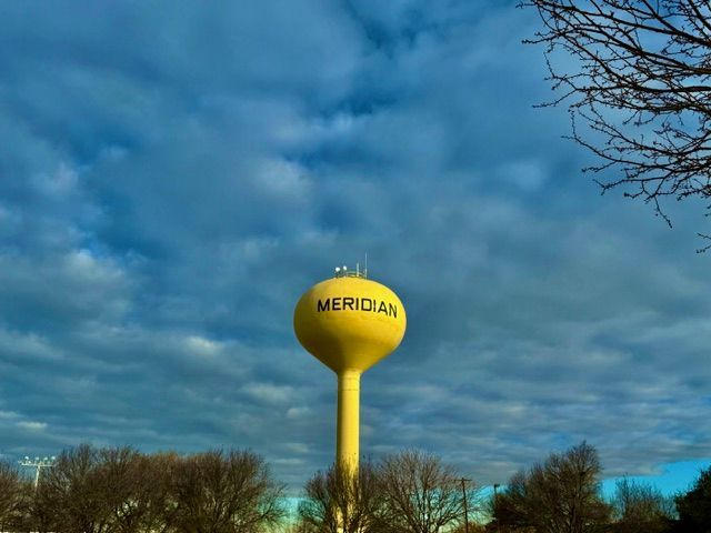 A yellow water tower with the word Meridian on it
