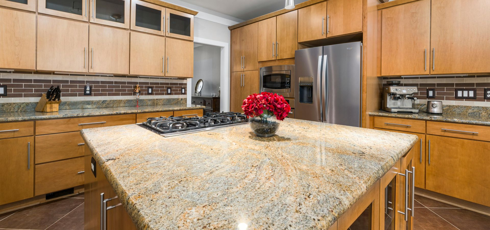 Kitchen with light wood cabinets, granite countertops, and a stainless steel refrigerator.