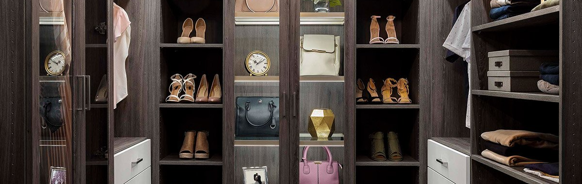 A walk-in closet with shelves and clothing, showing shoes, purses, and garments.