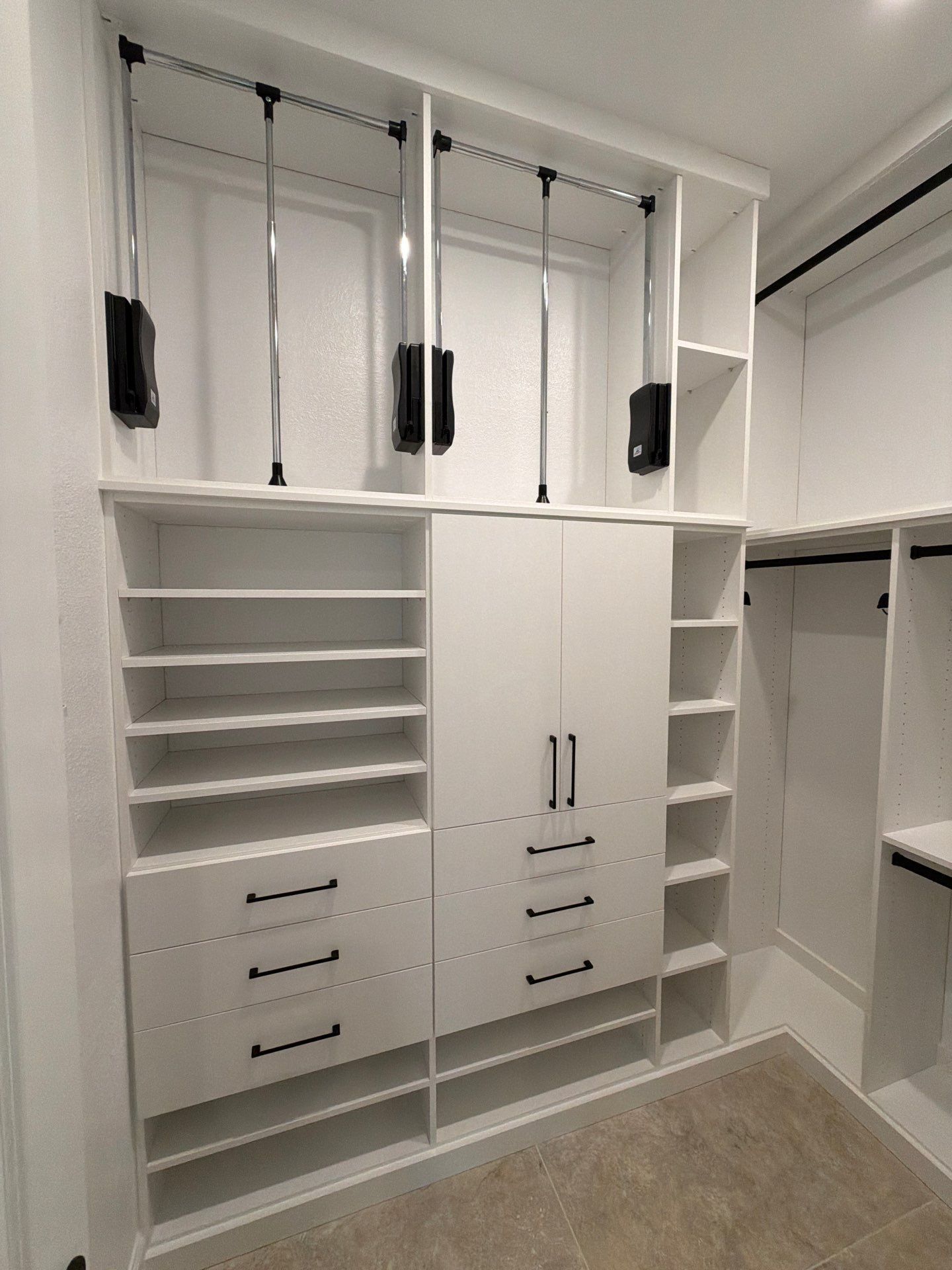 White custom walk-in closet with shelves, drawers, hanging rods, and beige carpet flooring
