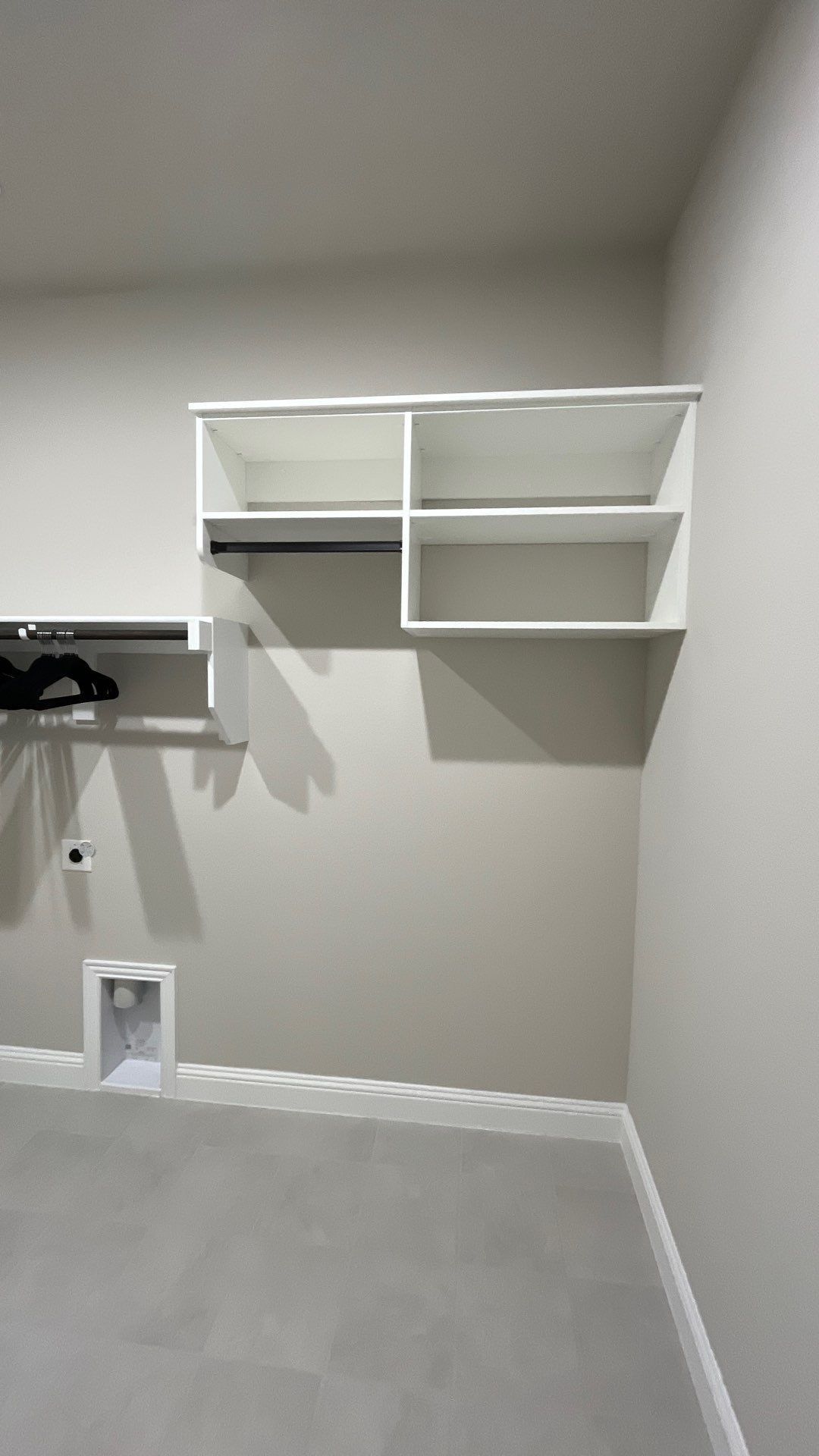 Empty room with white walls, built-in wall shelves, and light gray carpet.
