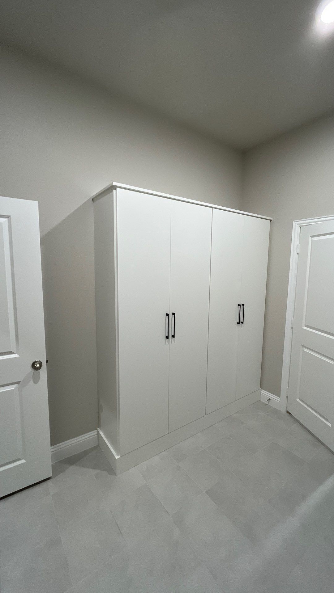 Empty white bedroom with a large closet and two doors on a gray carpeted floor