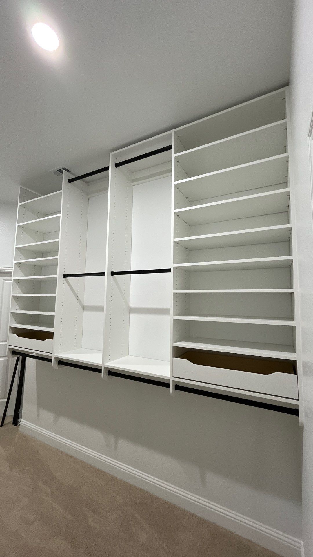 White wall-mounted shelving system with many empty compartments in a room