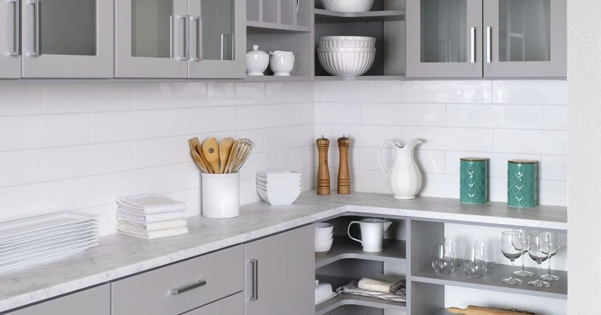 a kitchen with gray cabinets , white counter tops , and a pantry .