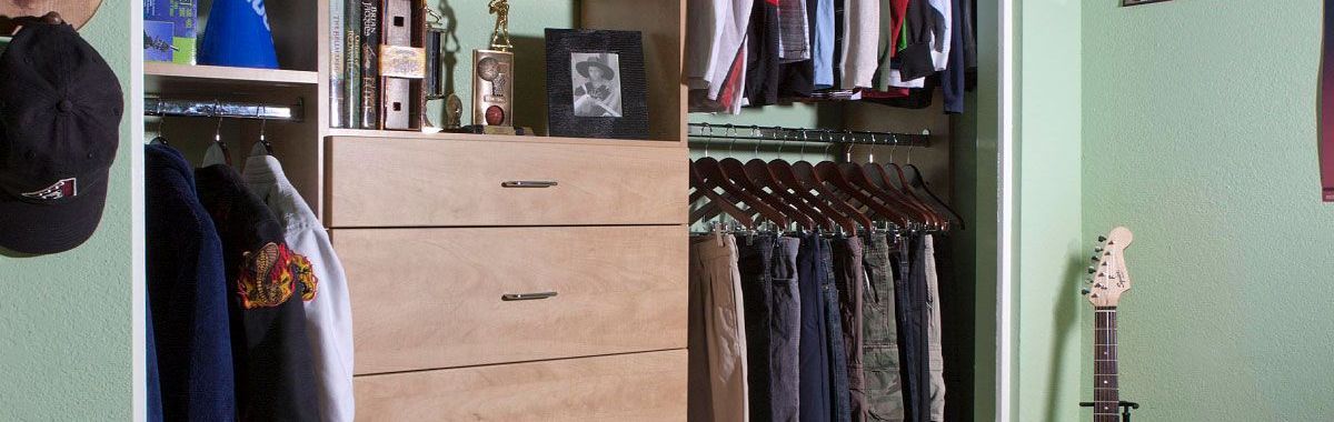 A small reach-in closet filled with clothes and a guitar.
