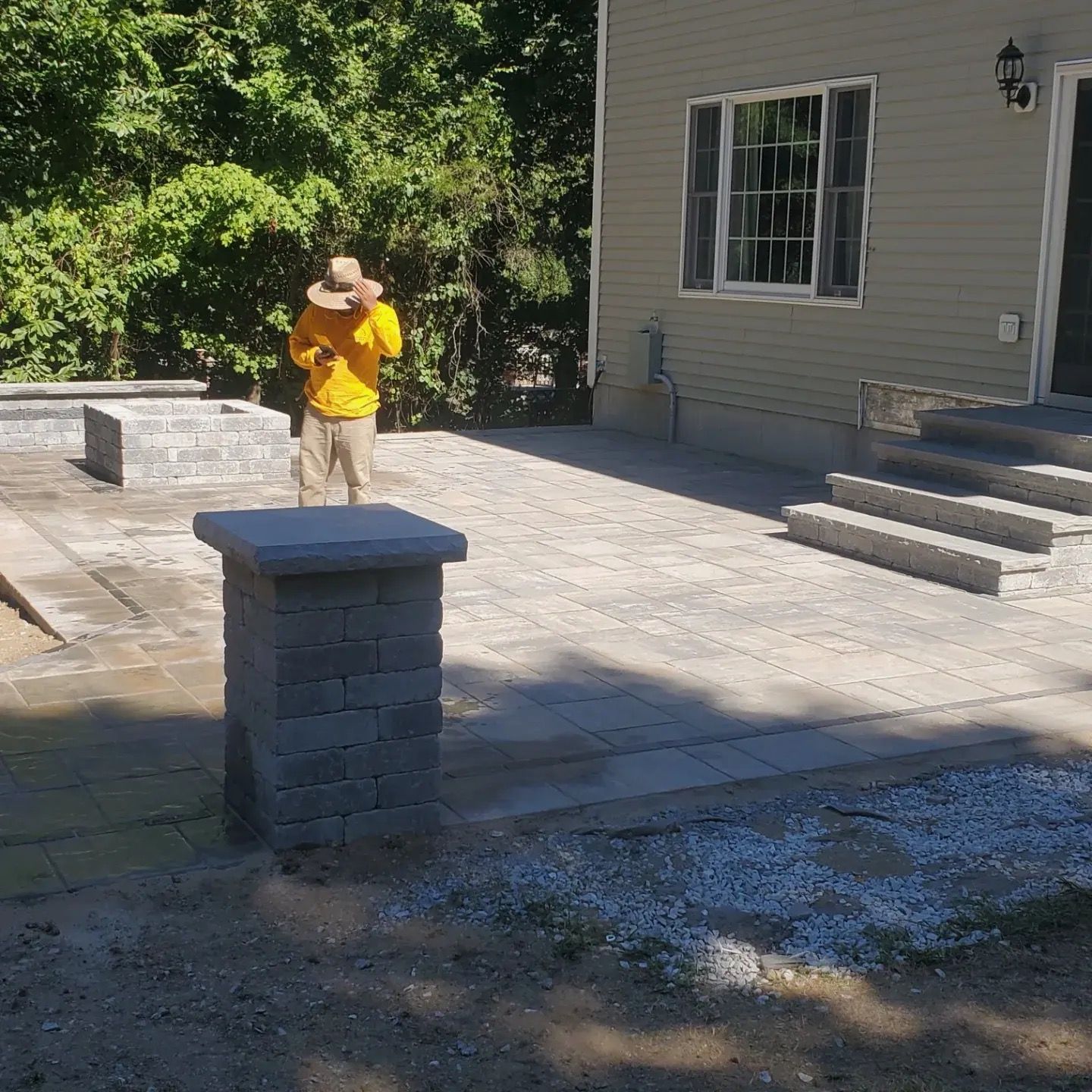 A man standing on a brick pillar in front of a house