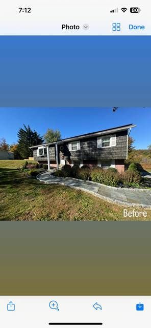 A phone screen shows a picture of a house before being remodeled.
