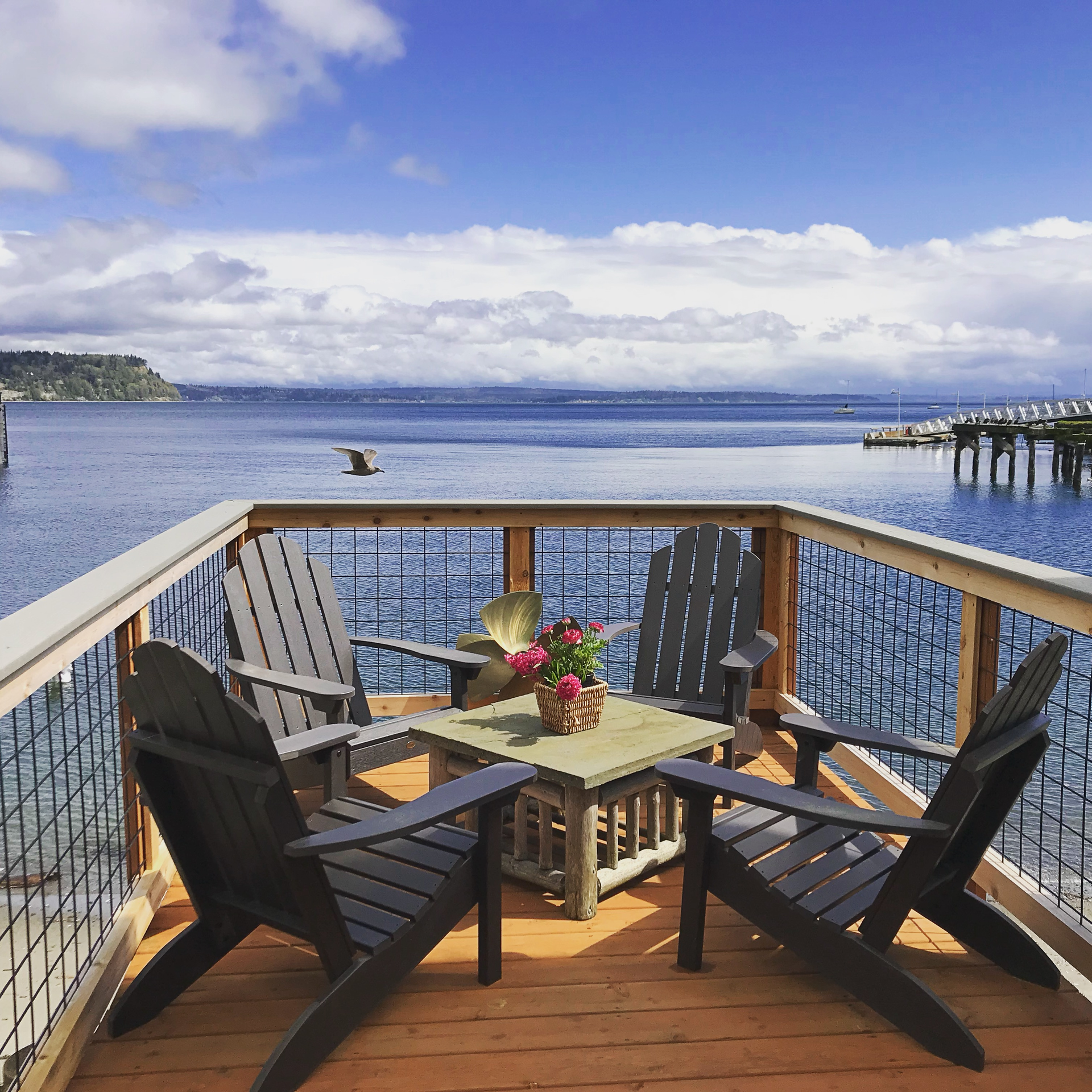 A balcony with two chairs and a table overlooking the water