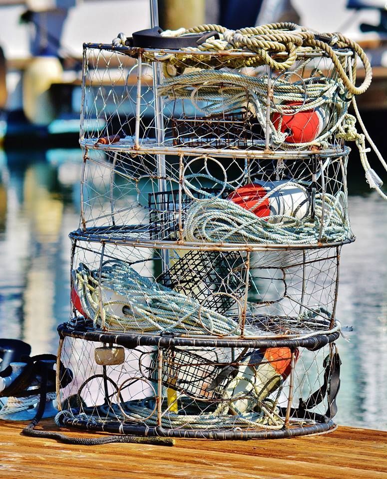 A stack of lobster traps sitting on top of a wooden dock.