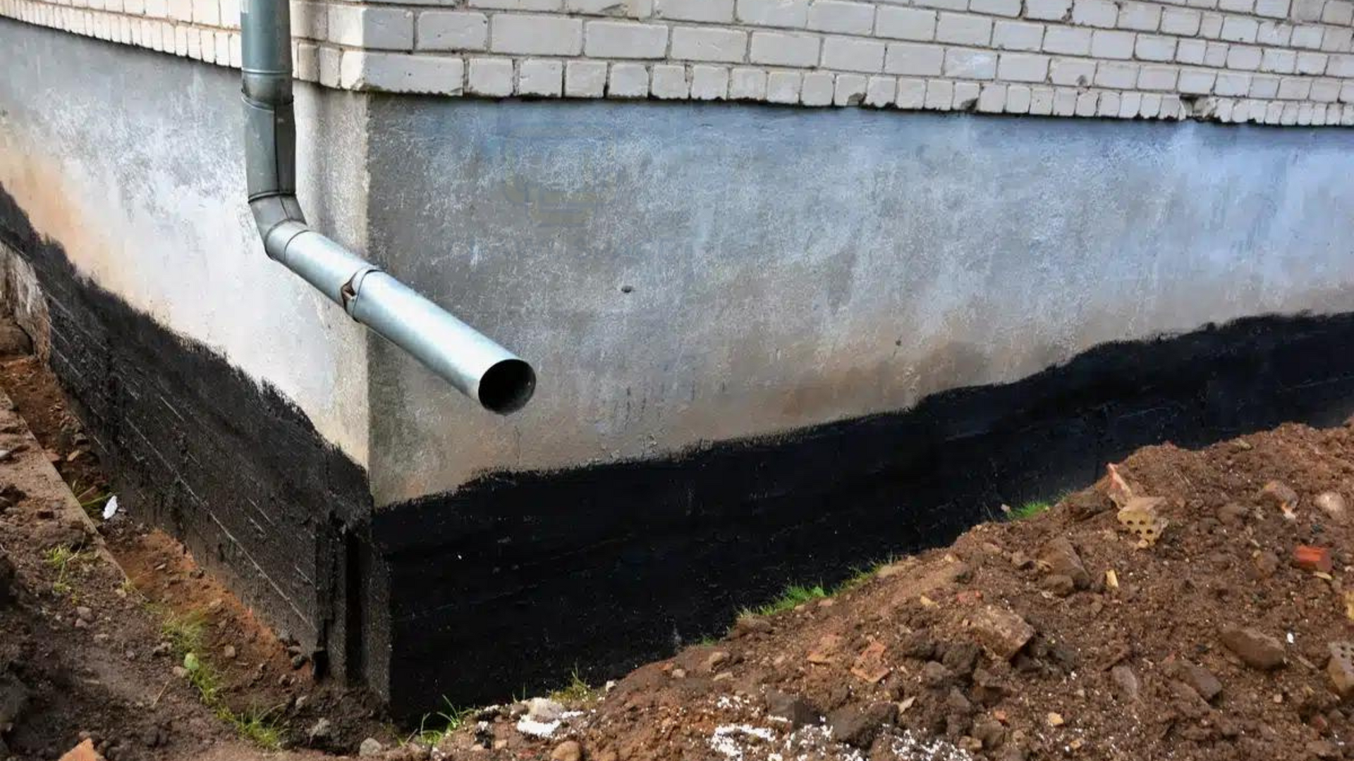 A drainpipe is attached to the side of a brick building.