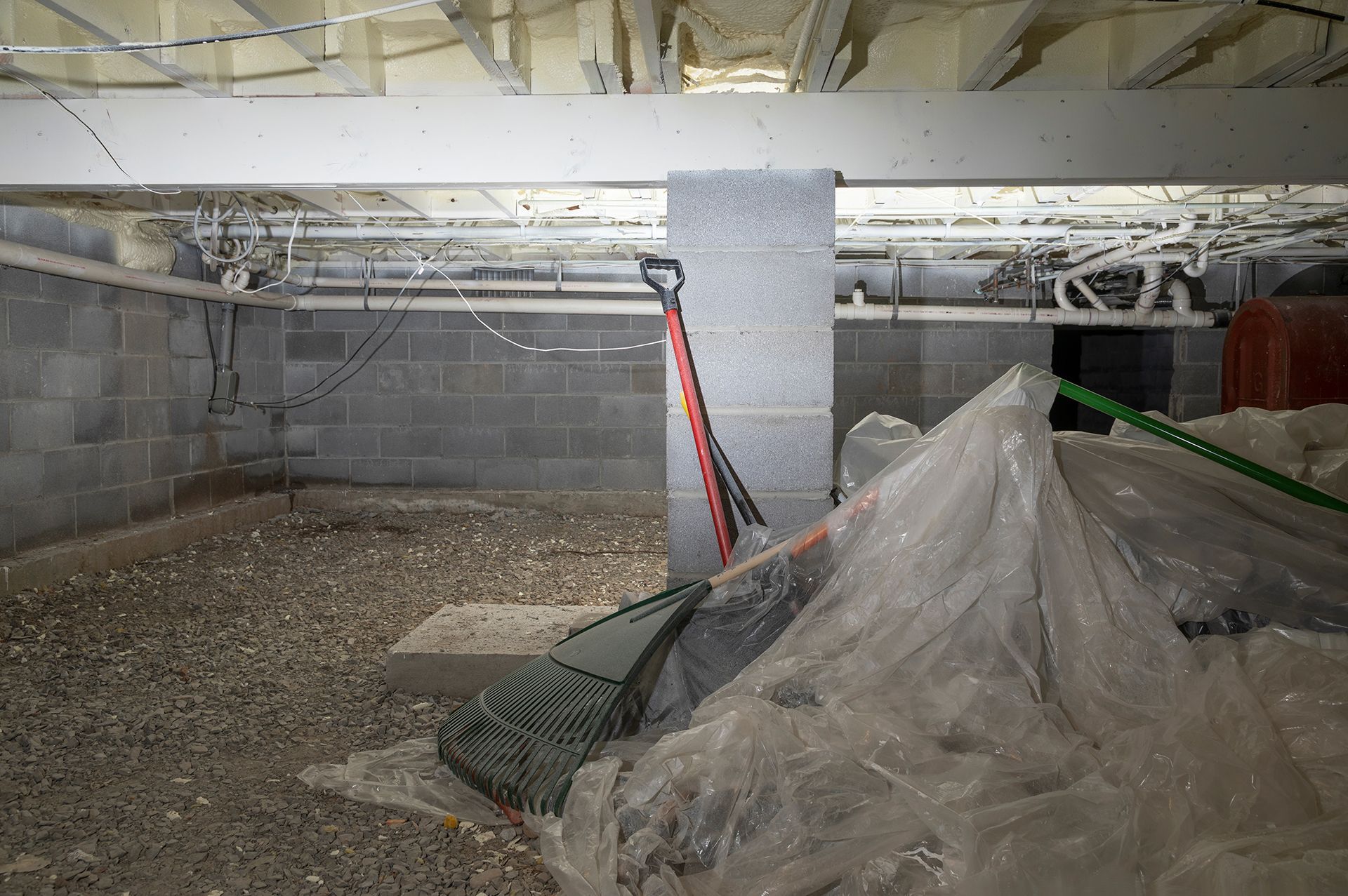 A shovel is sitting on top of a pile of plastic in a basement.