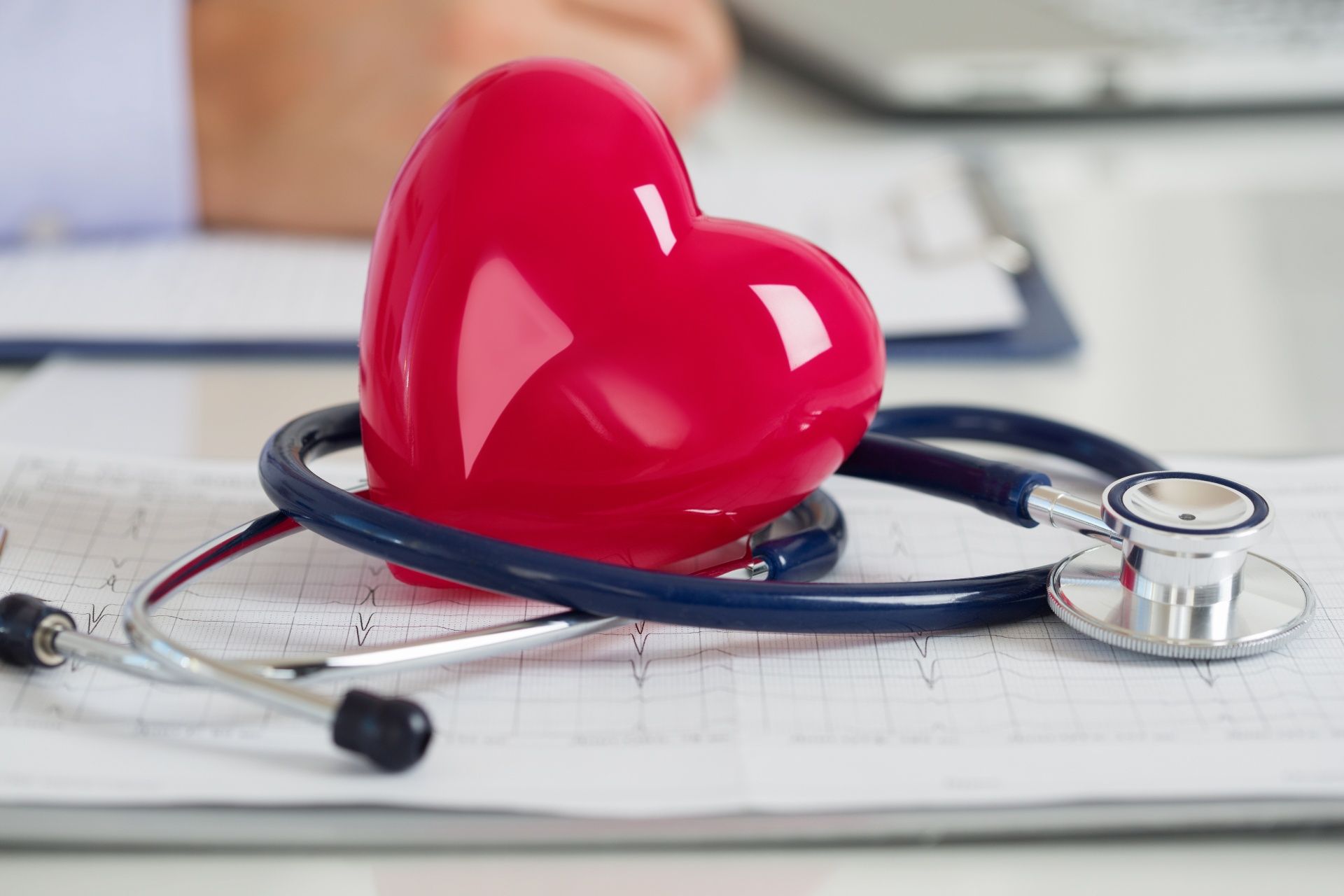 A red heart is sitting on top of a stethoscope on a clipboard.