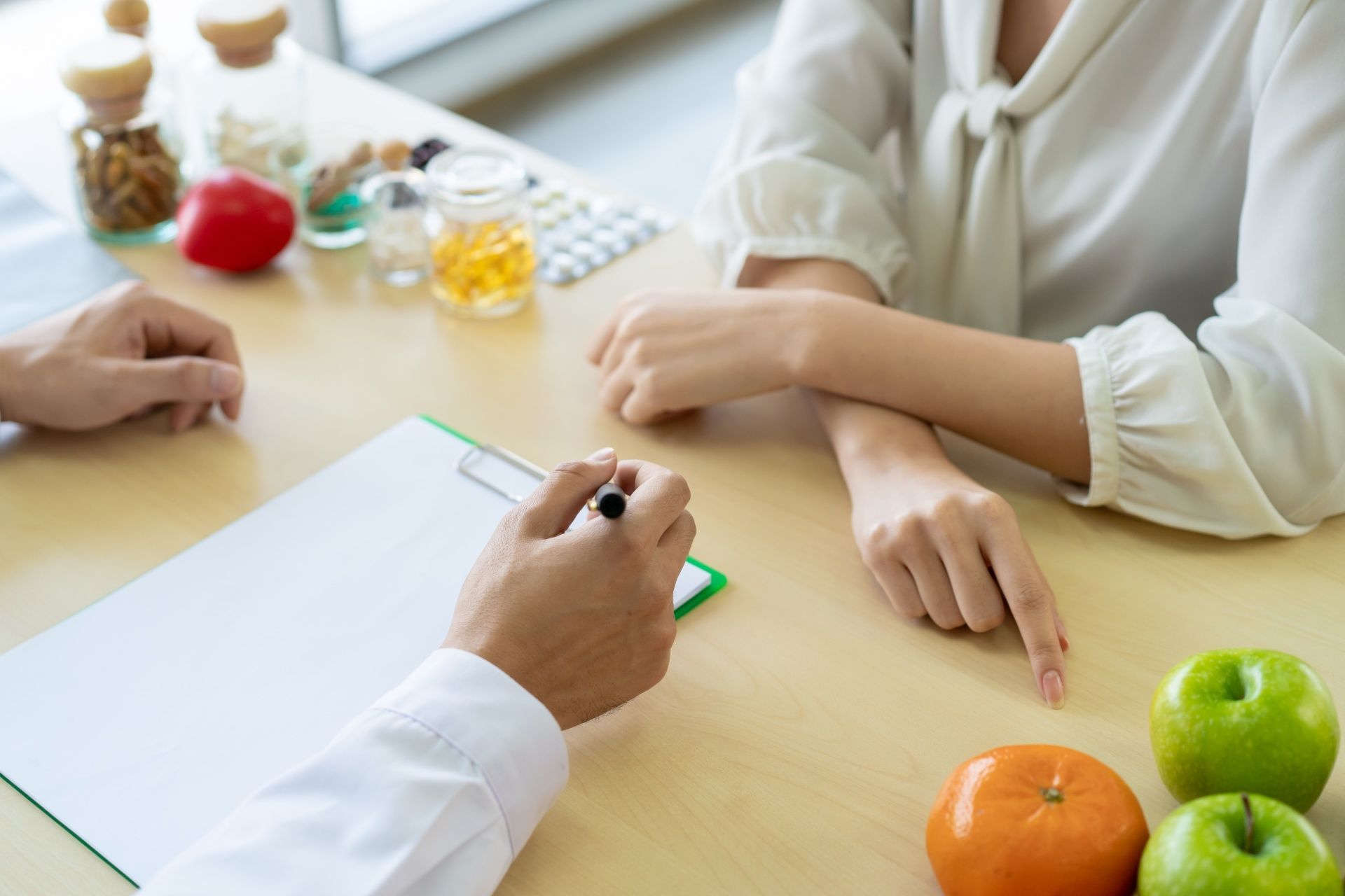 A woman is sitting at a table talking to a doctor.
