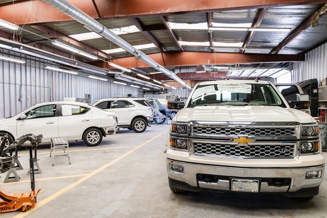Truck in auto body shop, other vehicles, concrete floor, overhead lights.