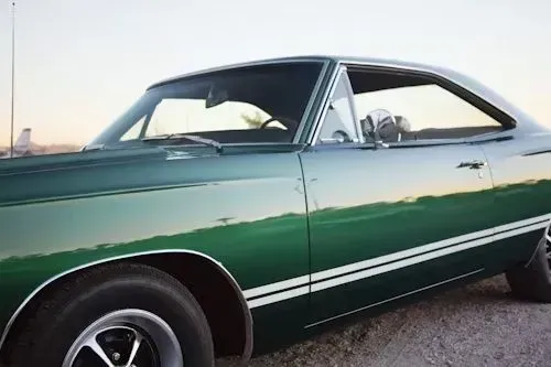 Green classic car with white stripes parked outdoors.