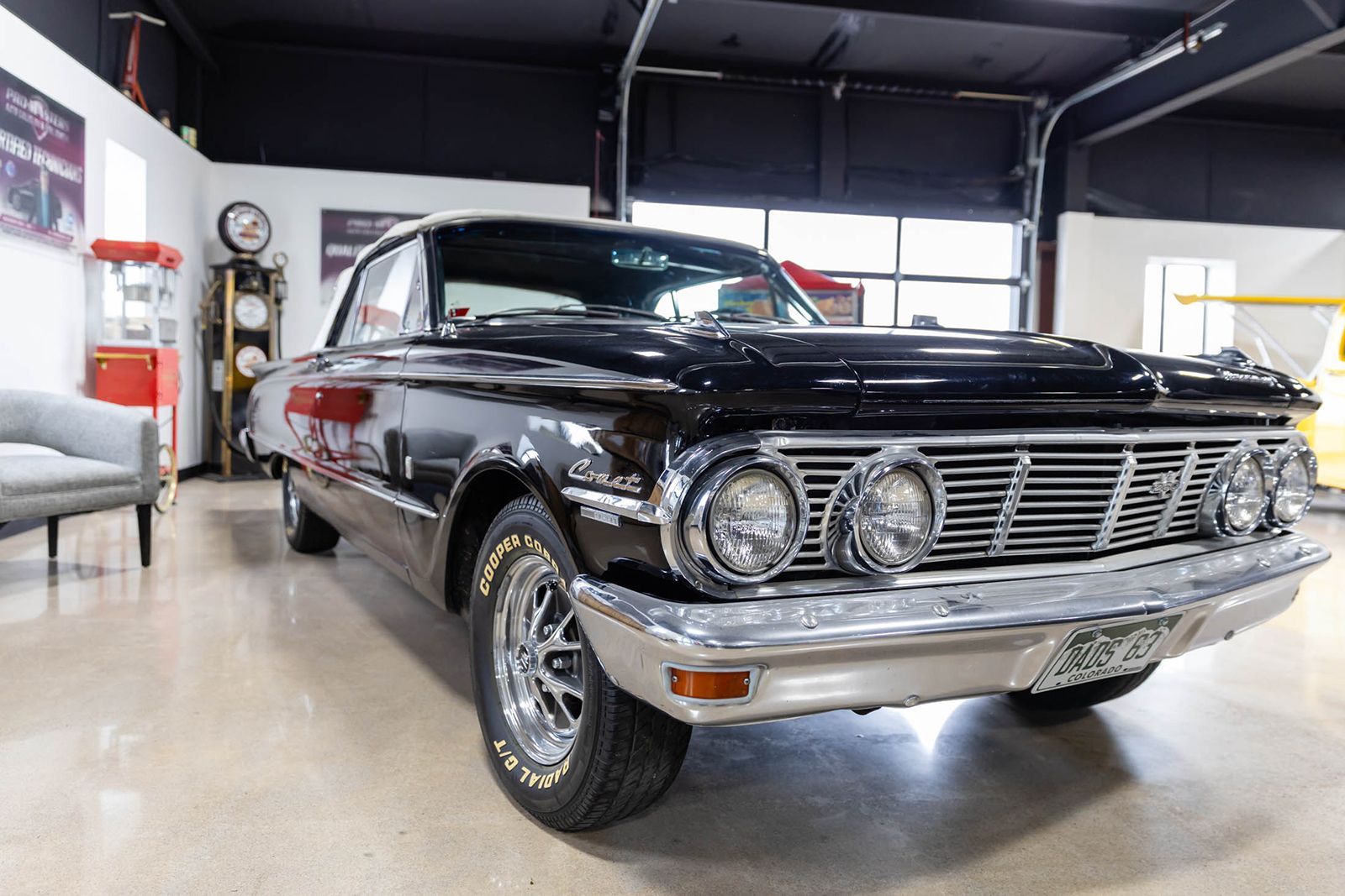 Classic black vintage car parked in a garage, front view with chrome grille and headlights