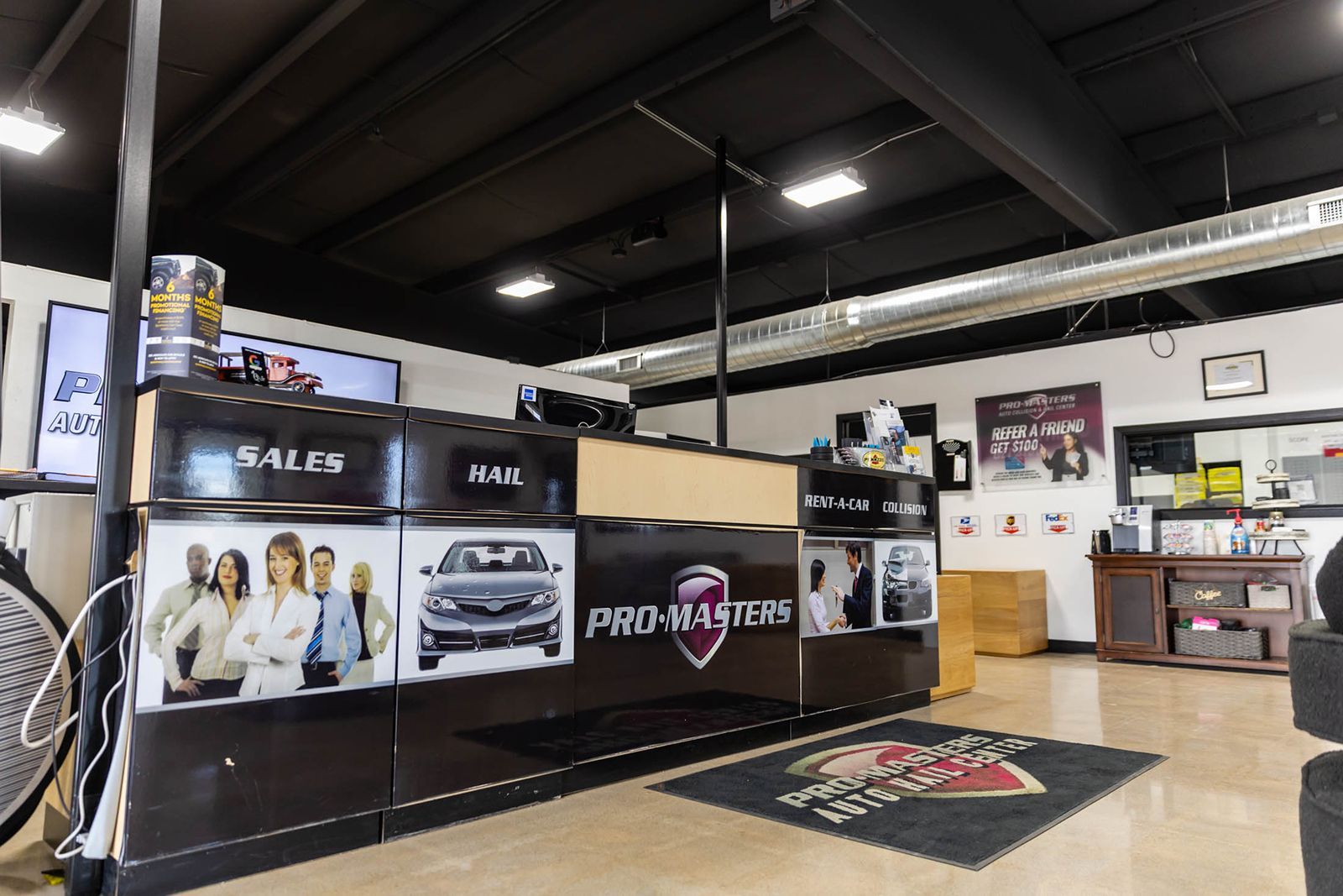 Auto shop showroom with car displays, promotional banners, and a service counter under bright industrial lighting