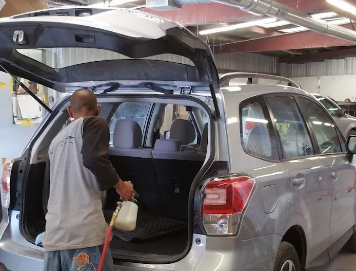 Person loading a bag into the open trunk of a silver SUV in a garage