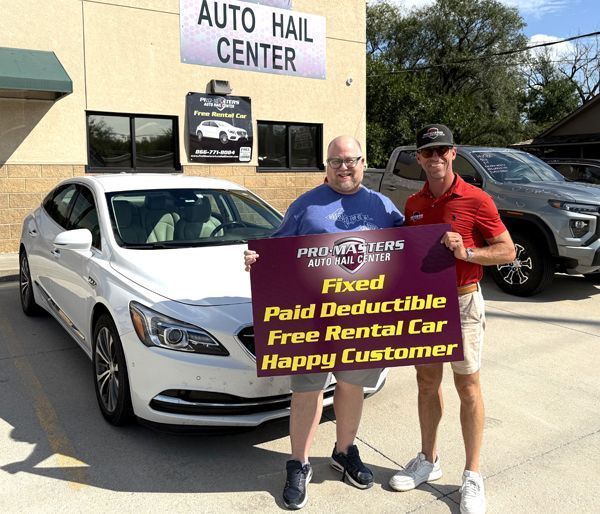 Two men holding a sign in front of a white car at 