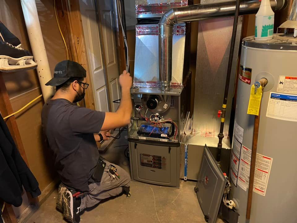 A man is working on a heating system in a basement.