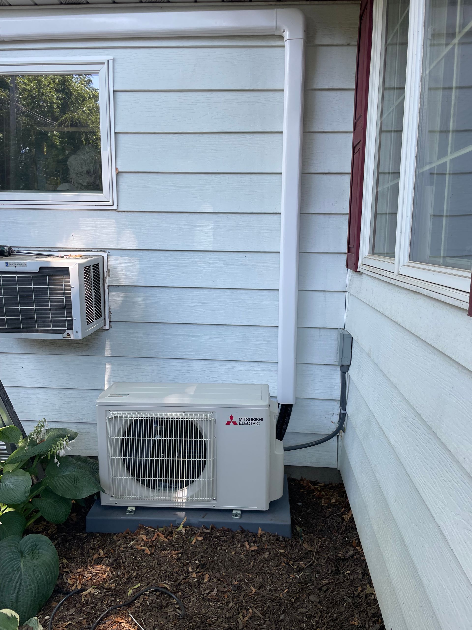 A mitsubishi air conditioner is installed on the side of a house
