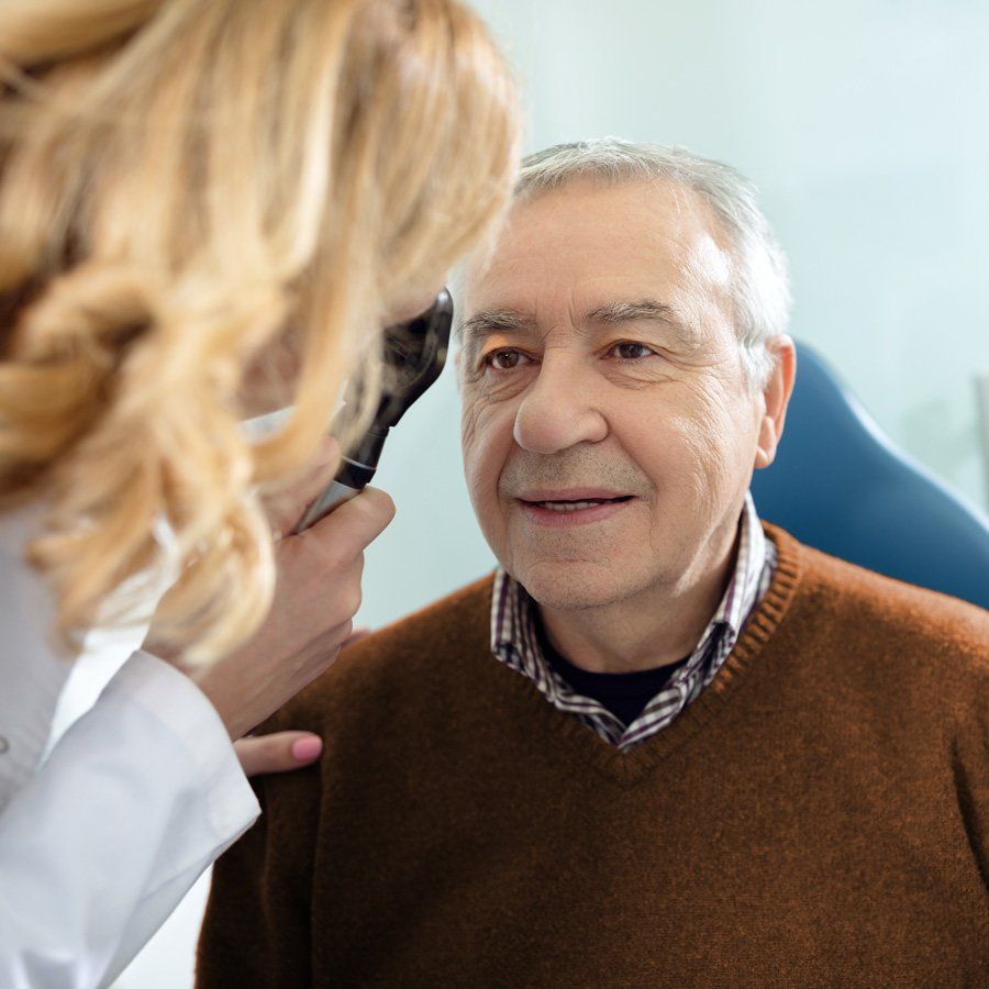 Eye doctor looking into man'e eye with handheld eye equipment
