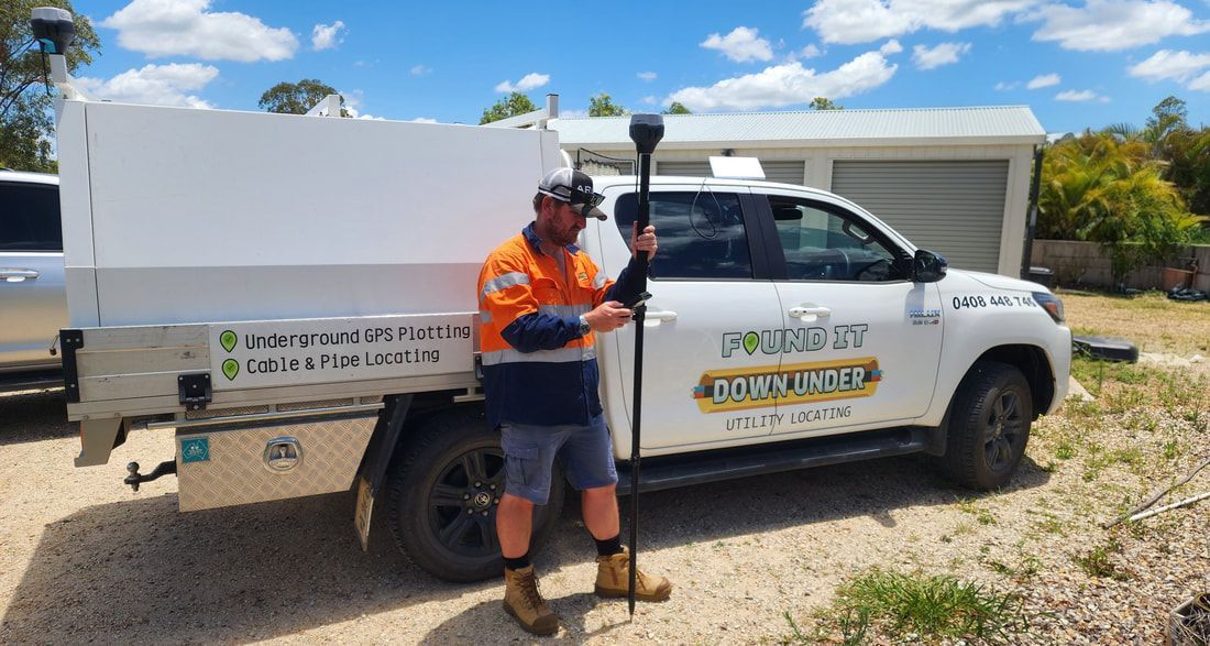 Man Holding a GNSS Device Stands by a White Truck With Business Logos — Found It Down Under in Glenwood, QLD