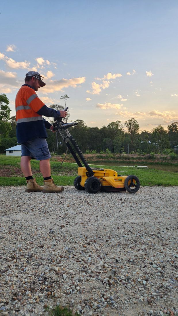 Man in Work Clothes Mowing Gravel Path With a Yellow Machine Against a Sunset Backdrop — Found It Down Under in Glenwood, QLD