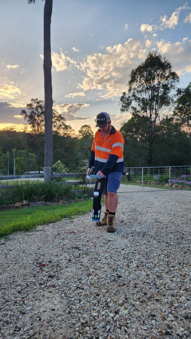 Man in Work Clothes Uses a Power Tool on a Gravel Path — Found It Down Under in Glenwood, QLD
