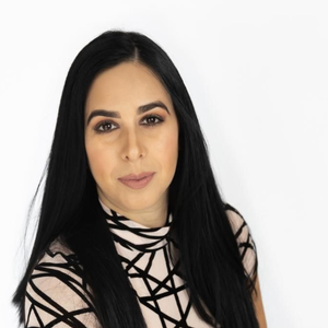 Woman in a patterned top with arms crossed against a white background
