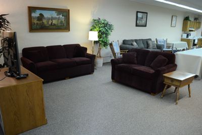 Cozy living room with brown sofas, a coffee table, lamp, and wall art on carpeted floor.