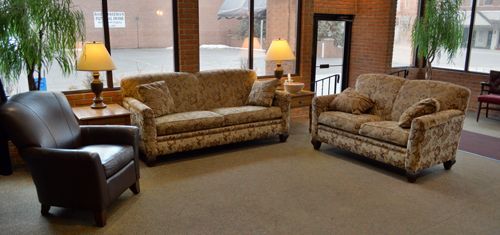 Cozy lobby with brown sofas and armchairs, lamps, and large windows.