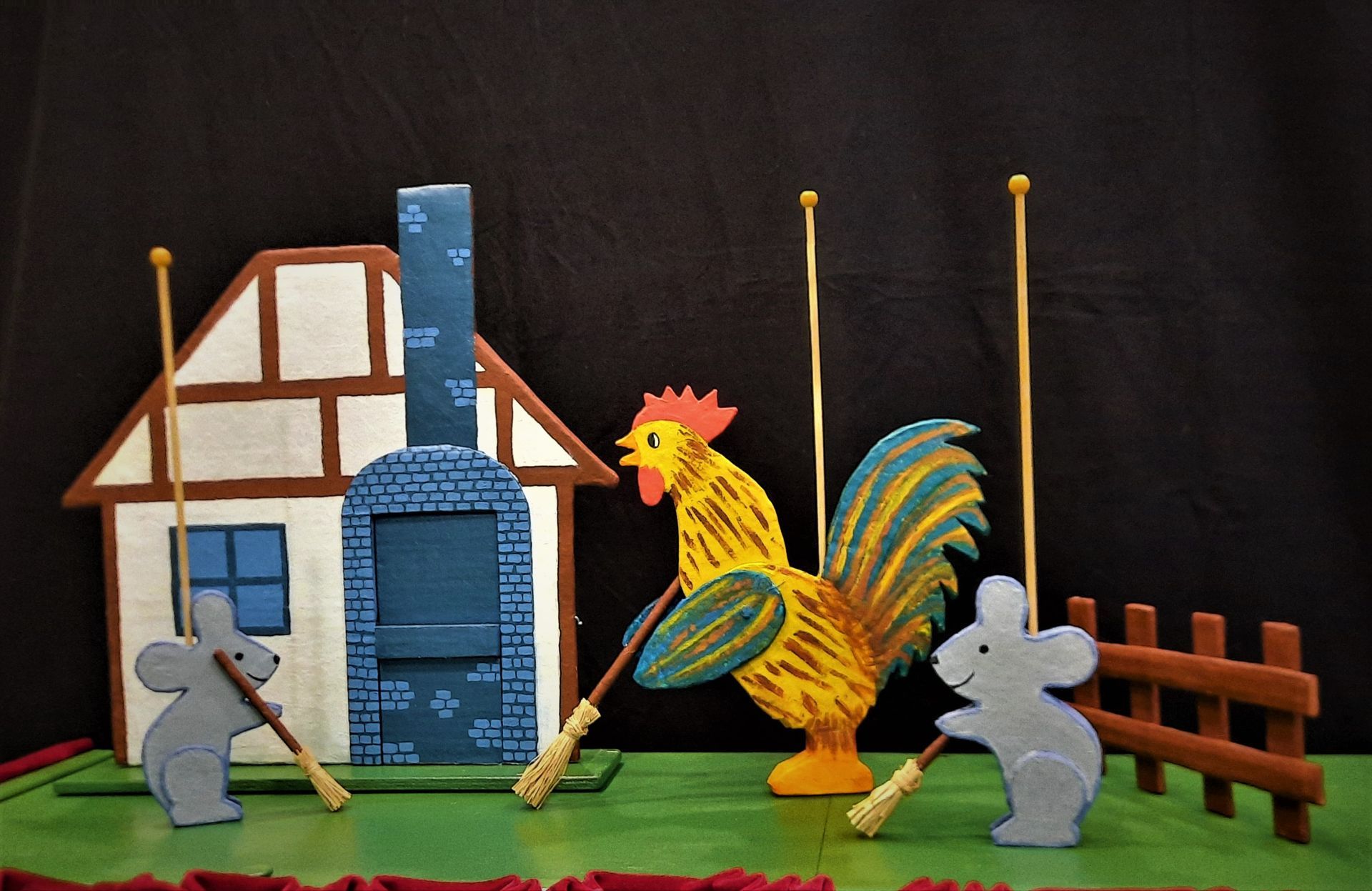 Ein Hahn und zwei Mäuse stehen vor einem Haus