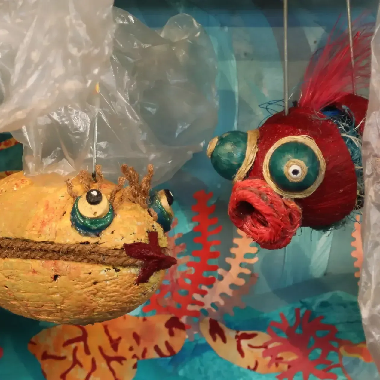 Ein gelber Fisch und ein roter Fisch hängen an einer Plastiktüte