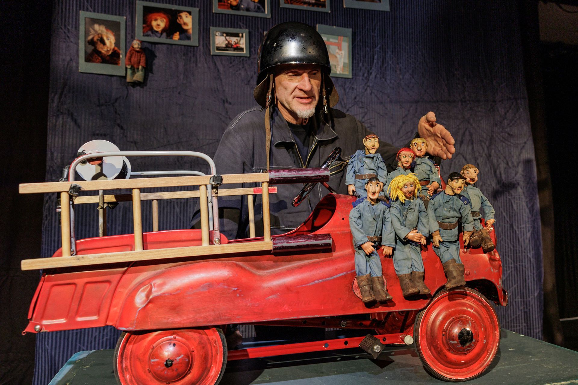 Ein Mann mit Helm sitzt in einem Spielzeug-Feuerwehrauto