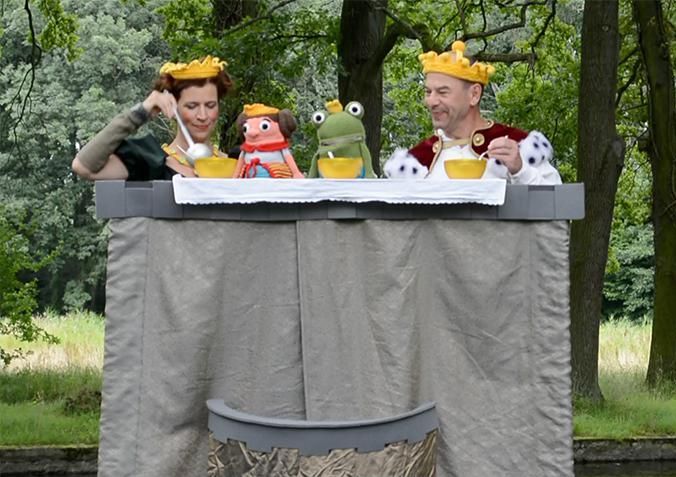 Ein Mann und eine Frau spielen ein Puppenspiel mit Fröschen