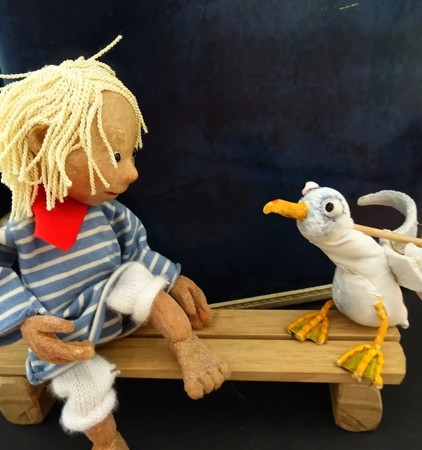 Eine Puppe und ein ausgestopfter Vogel sitzen auf einer Holzbank